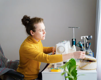 Female seamstress using sewing machine while working at home