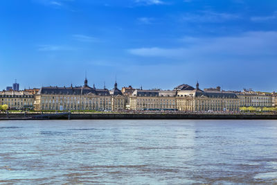 Buildings by river against sky