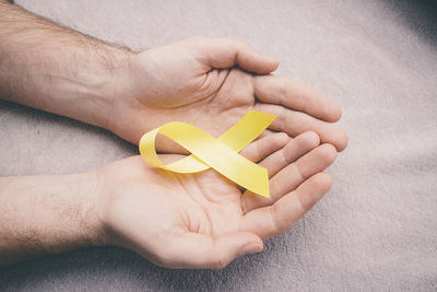 Close-up of man holding yellow hand