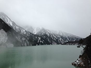 Scenic view of lake by snowcapped mountains against sky