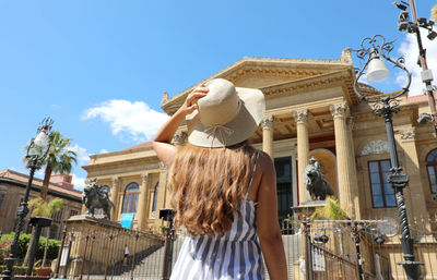 Woman standing by traditional building against sky