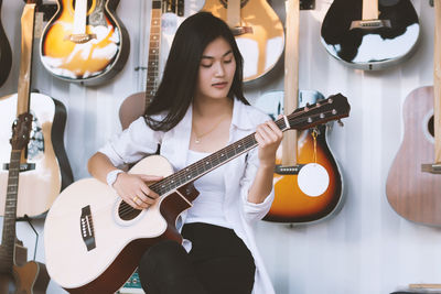 Young woman playing guitar in store