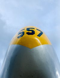 Low angle view of yellow telephone against sky