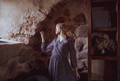 Woman standing against wall at home