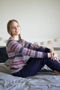 Portrait of a smiling young woman sitting on bed