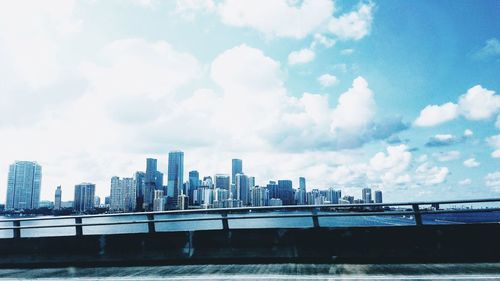 Bridge over river by buildings against sky in city