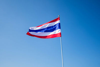 Low angle view of thai flag waving against clear blue sky