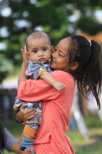 The older sister is holding the younger brother 