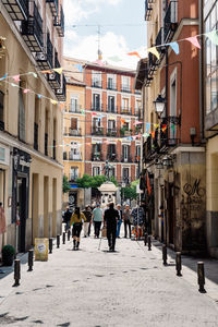 People walking on street amidst buildings in city