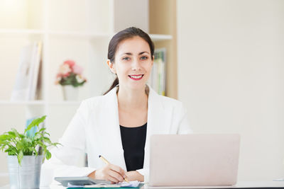 Portrait of young woman using phone on table