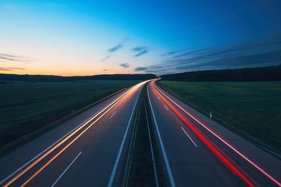 Light trails on road against sky