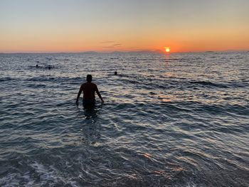 Silhouette man on beach against sky during sunset