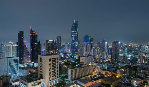 Illuminated modern buildings in city against sky