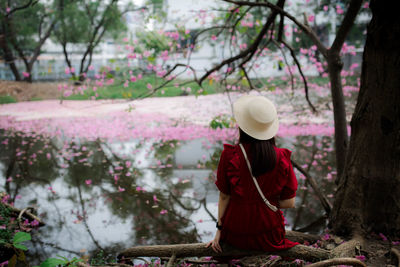 Woman standing by pink flowering tree