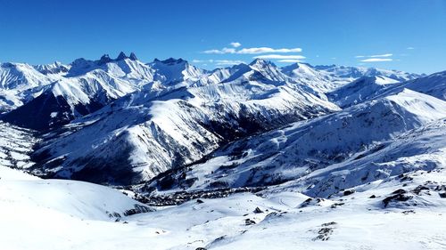 Scenic view of snowcapped mountains against blue sky