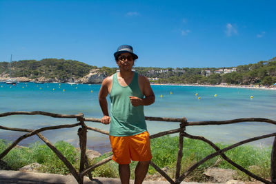 Full length portrait of man standing against blue sky