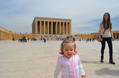 Girl with mother standing against historic building