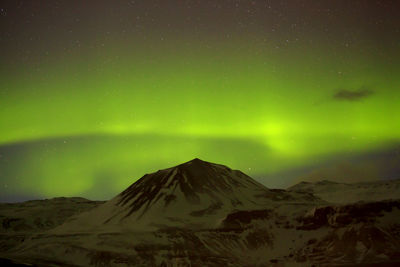 Green northern lights with snowy mountains in the foreground in iceland