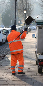Rear view of worker cleaning footpath