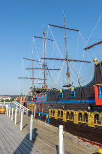 Sailboats on pier by sea against clear blue sky