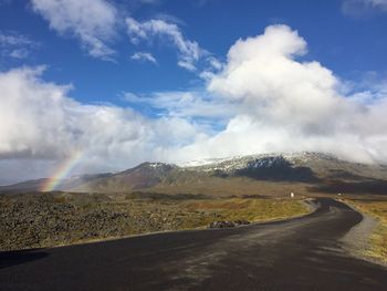 Scenic view of road by mountains against sky
