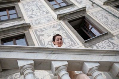 Low angle portrait of woman against building