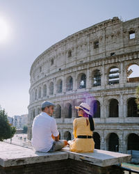 Rear view of couple by historical building against sky