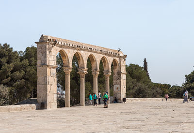 Group of people in front of historical building against clear sky