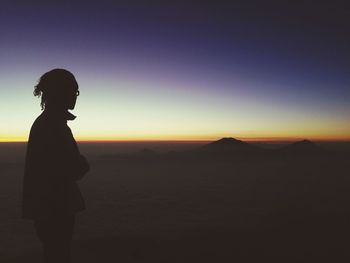 Silhouette man standing on mountain against sky during sunrise