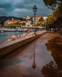 Street by river in city against sky