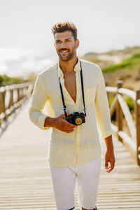 Young man holding camera while looking away