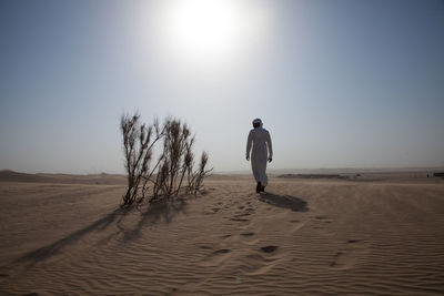 Full length of man on sand at beach against clear sky