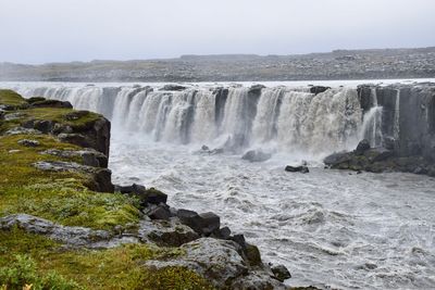 Scenic view of waterfall against sky