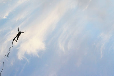 Low angle view of silhouette flying against sky