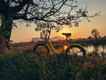 Bicycle on field against sky during sunset