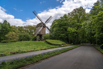 Traditional windmill by road against sky