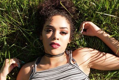 High angle portrait of beautiful young woman lying on grass