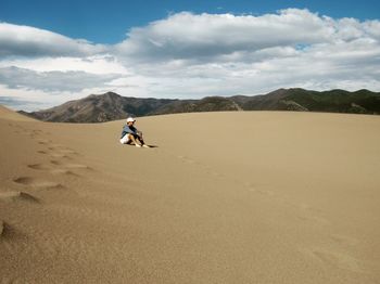 Teenage boy sitting on sand at desert