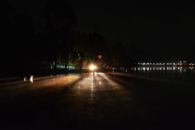 Empty road along illuminated street lights at night