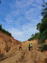 Rear view of people walking on road against sky