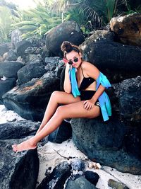 Young woman sitting on rocks at beach