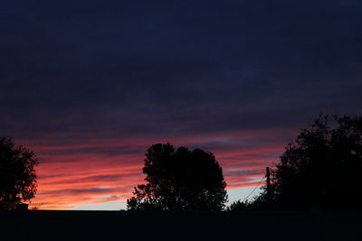 Silhouette trees against sky at sunset