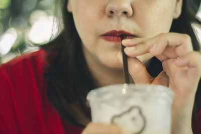 Close-up portrait of a young woman drinking glass