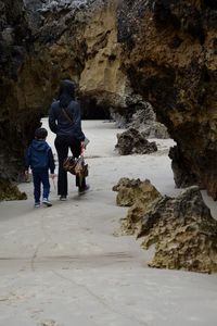 Mother and son walking through natural arch at beach