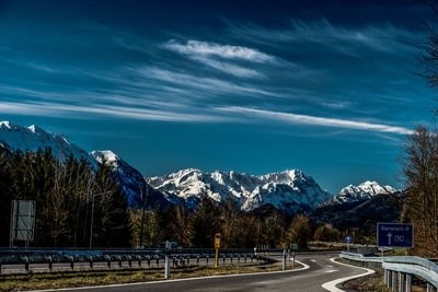 Road by trees against sky during winter