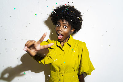 Portrait of young woman standing against yellow wall