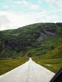 Road amidst green landscape against sky