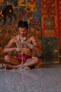 Full length of man working with rope while sitting in temple