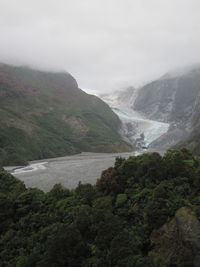 Scenic view of waterfall and mountains against sky