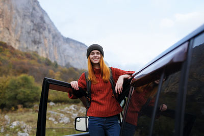 Portrait of smiling young woman standing on mountain